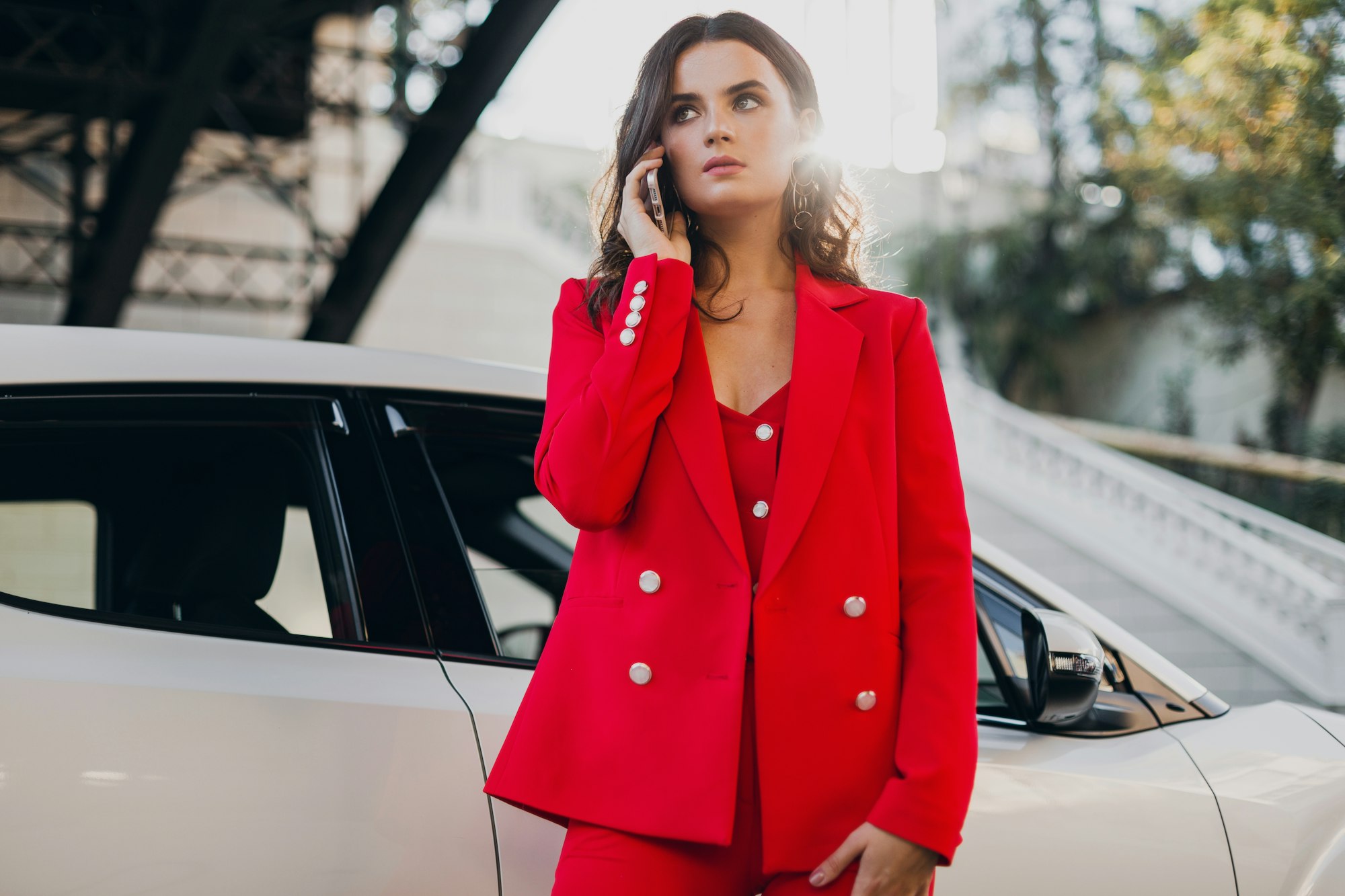 beautiful sexy woman in red suit posing at car talking on business on phone