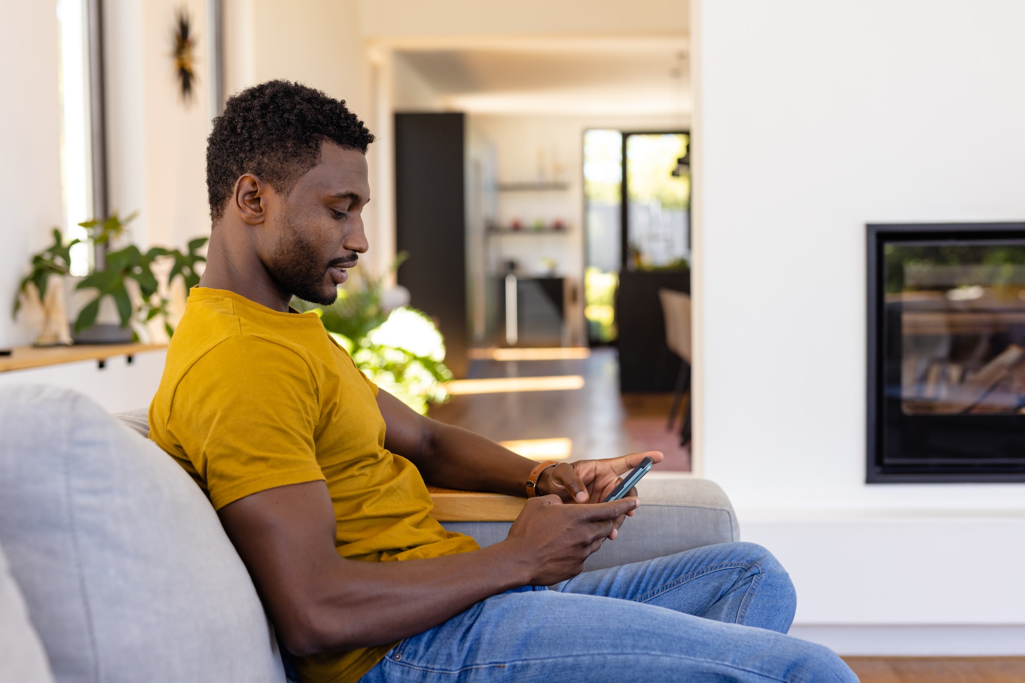Happy african american man using smartphone in living room