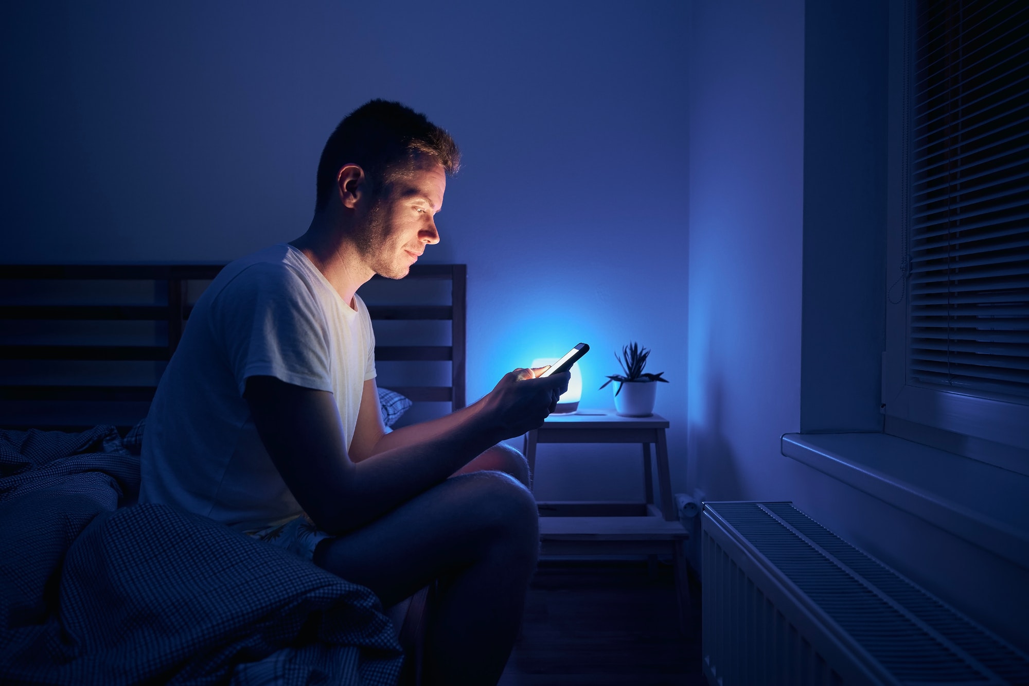 Man sitting in bedroom and using phone at night