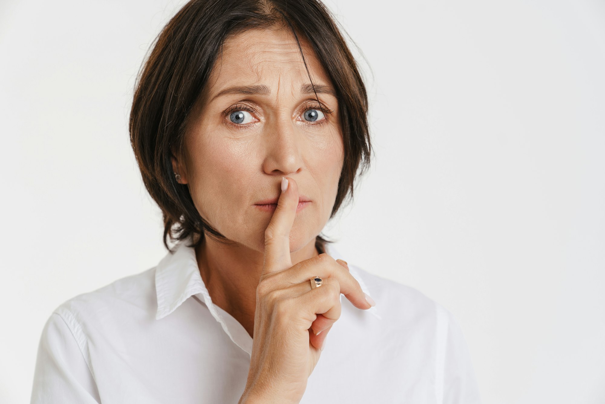 Mature brunette woman showing silence gesture at camera