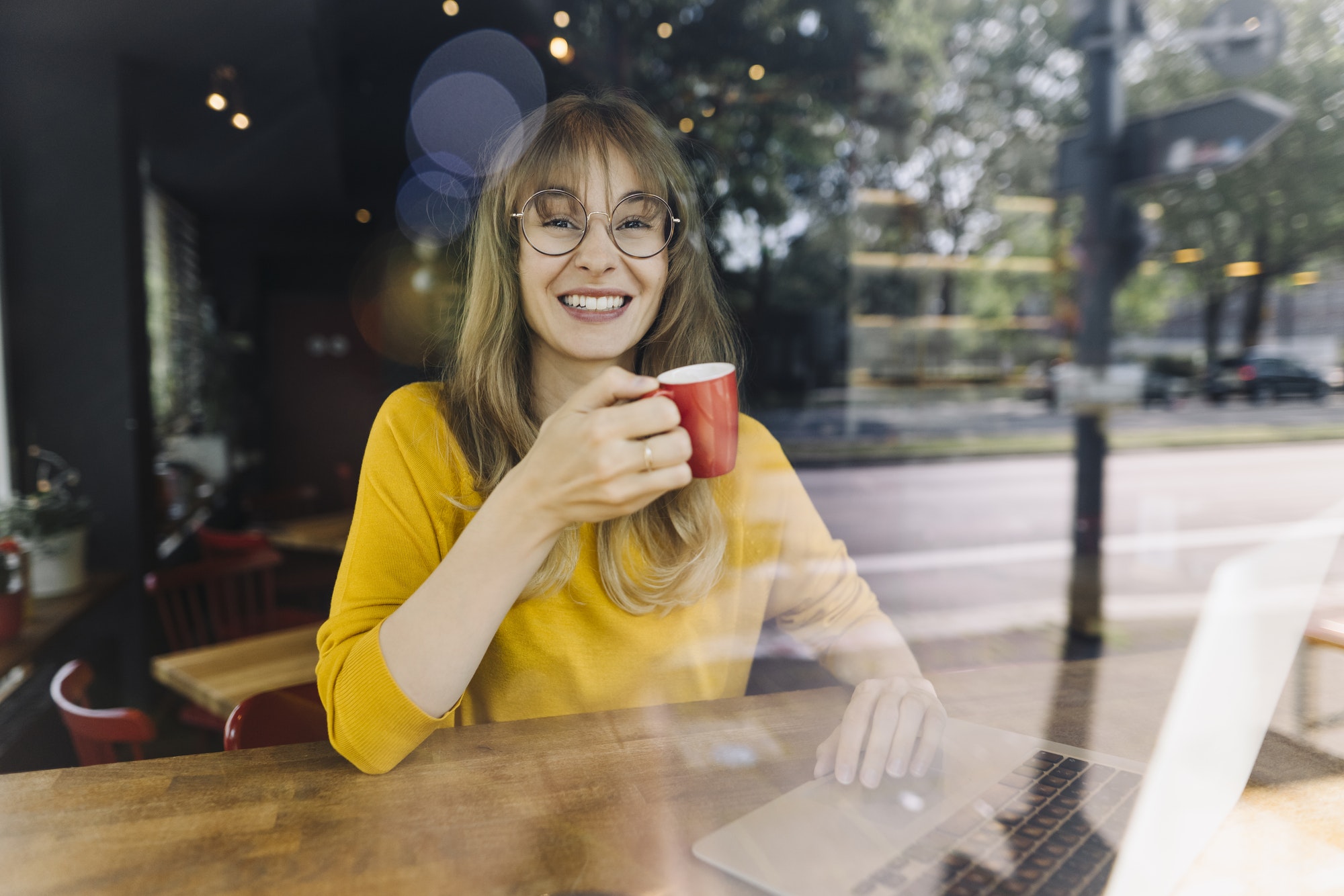 Portrait of smiling woman with laptop and coffee in a cafe