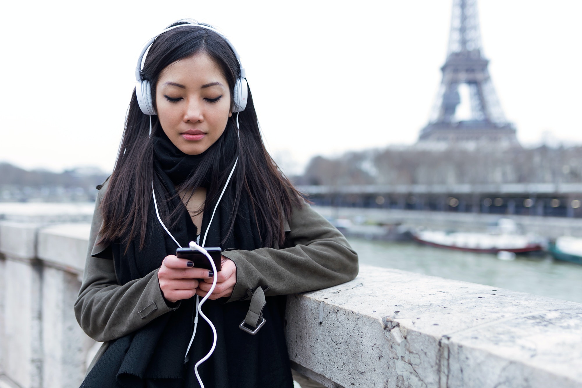 Pretty asian young woman listening to music with mobile phone in