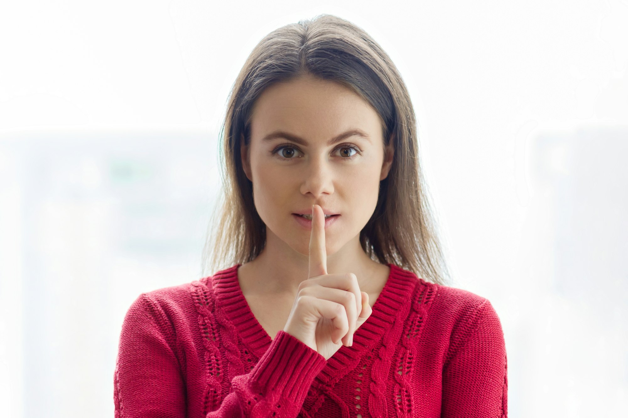 Sign secret, young woman showing silence sign with her finger on lips