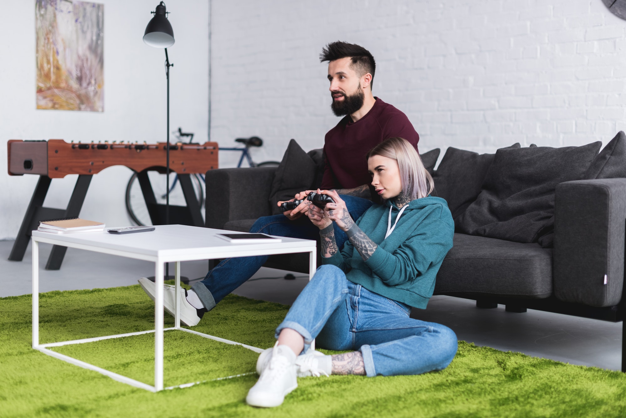 tattooed couple playing video game in living room