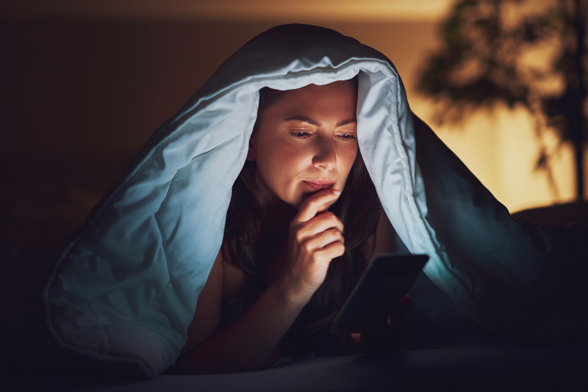 Woman at night in bed with phone