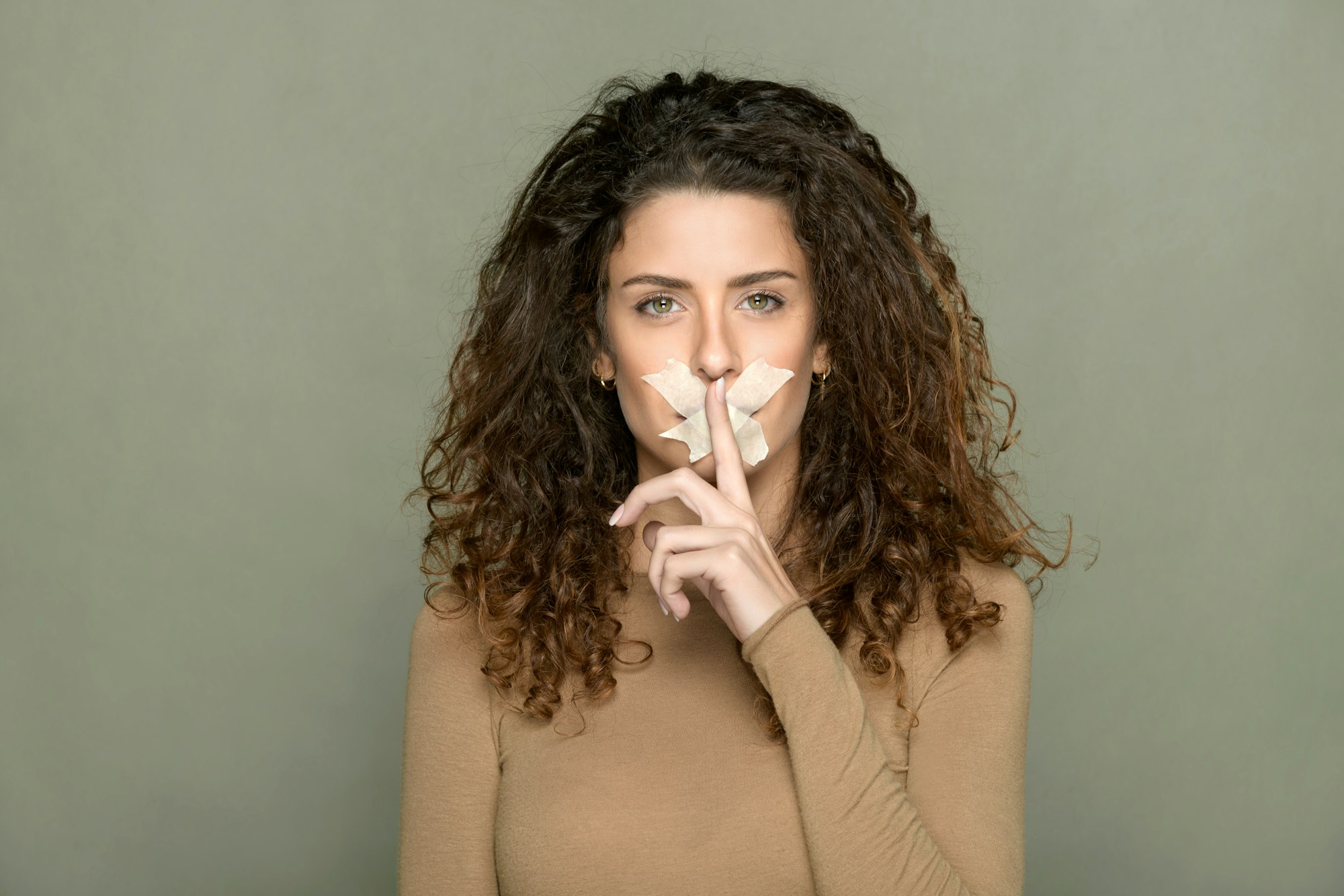 Woman with tape on lips showing silence gesture