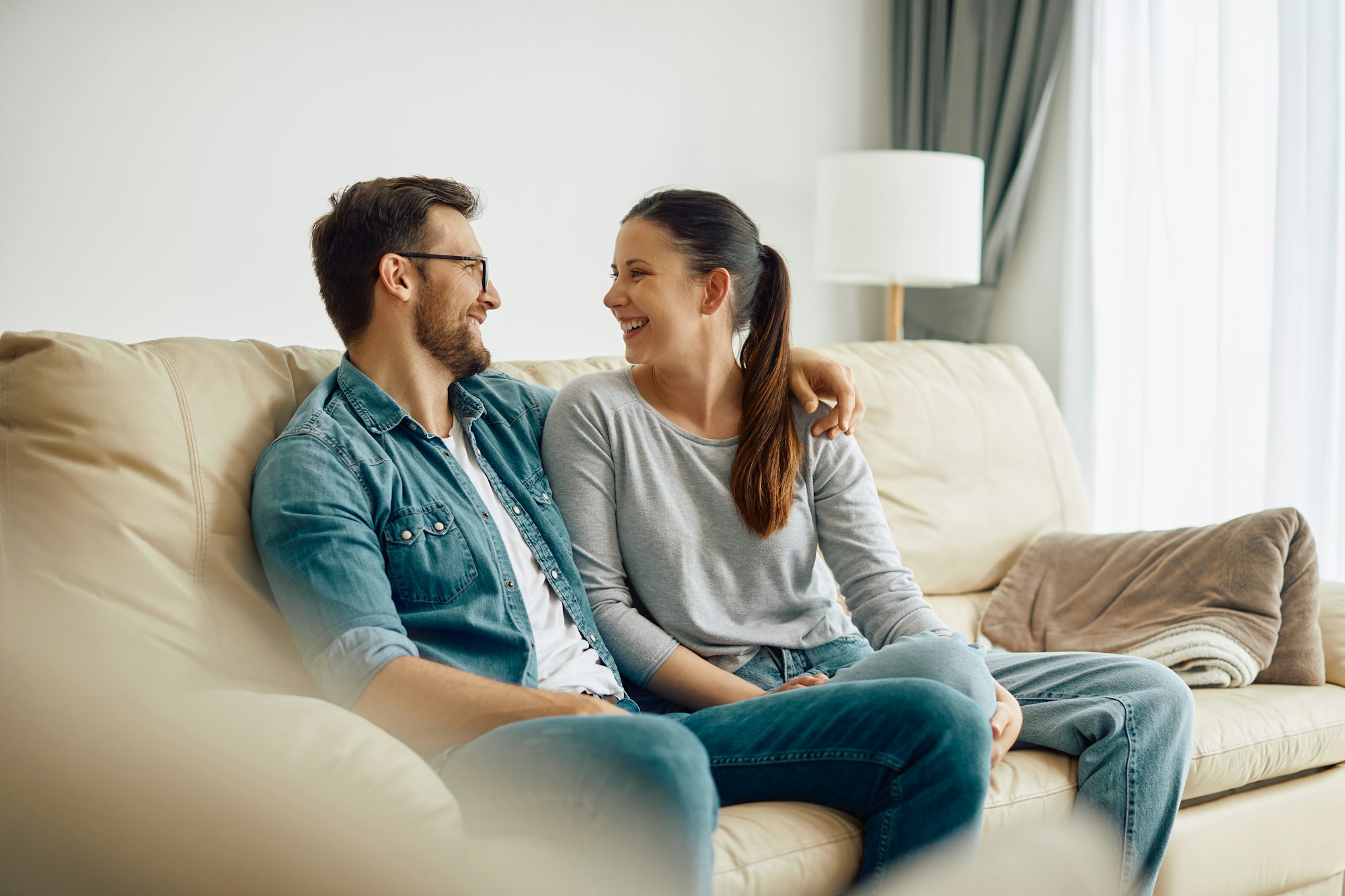 Happy couple talking while relaxing on the sofa at home.