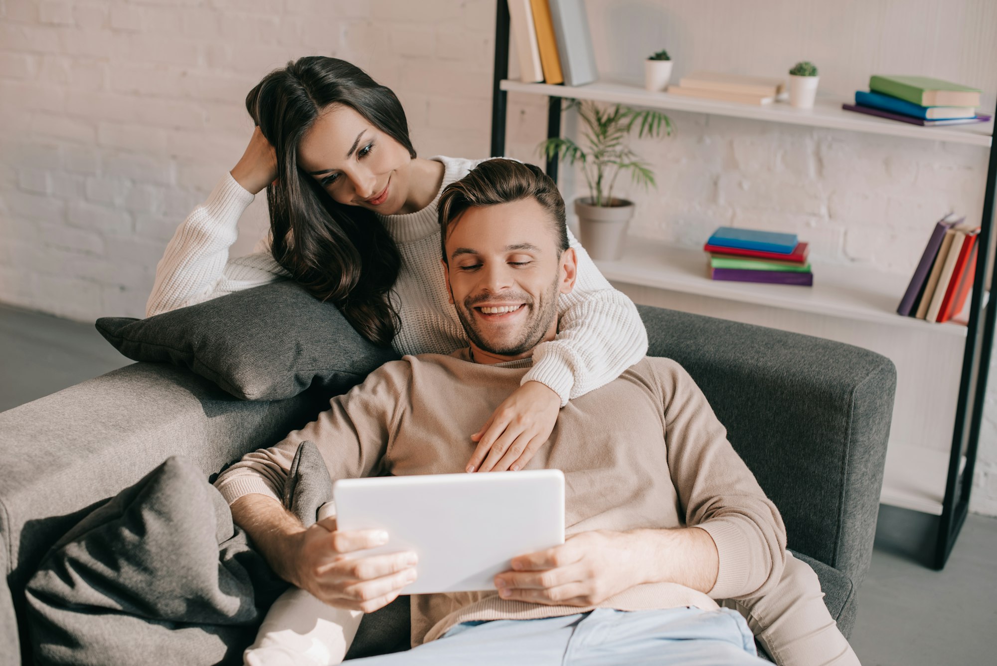 smiling young couple using tablet together on sofa at home