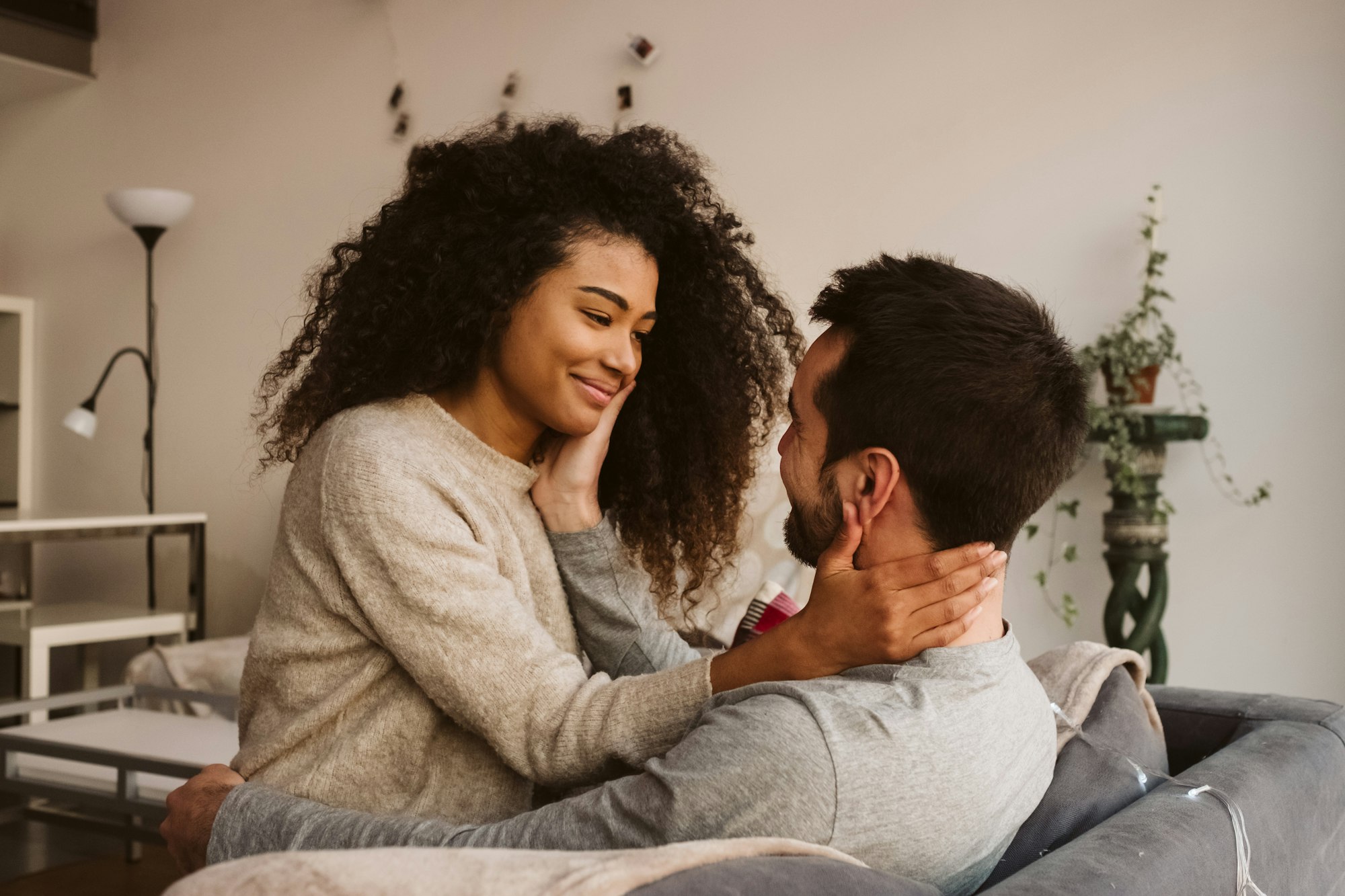 Young multiracial couple hugging on sofa