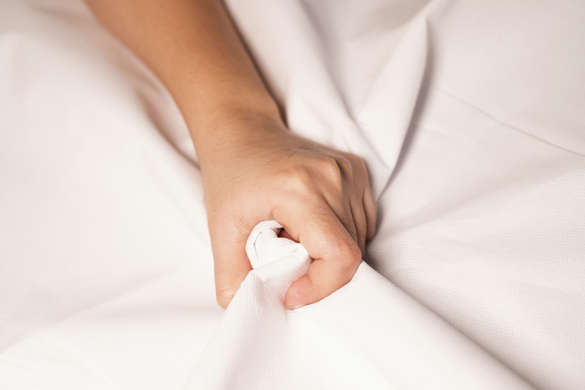 Woman hand squeezing bed sheets